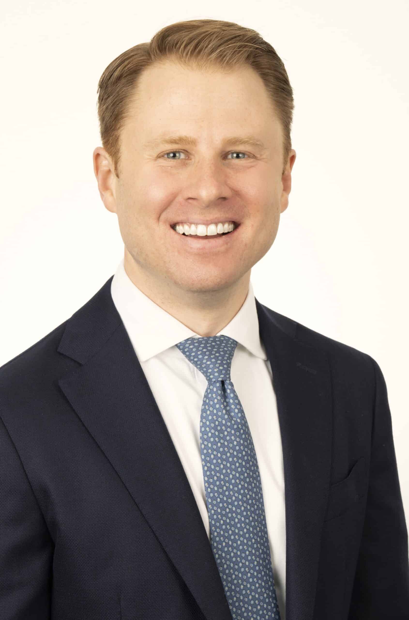 a man wearing a suit and tie smiling at the camera