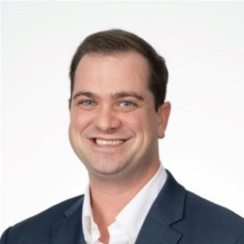 a man wearing a suit and tie smiling at the camera