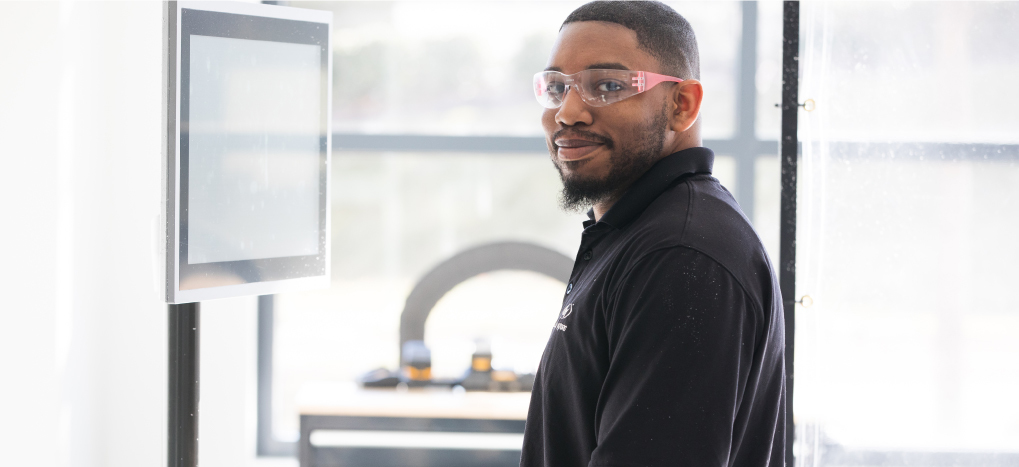 Manufacturing technician in safety glasses at a shop-floor control screen